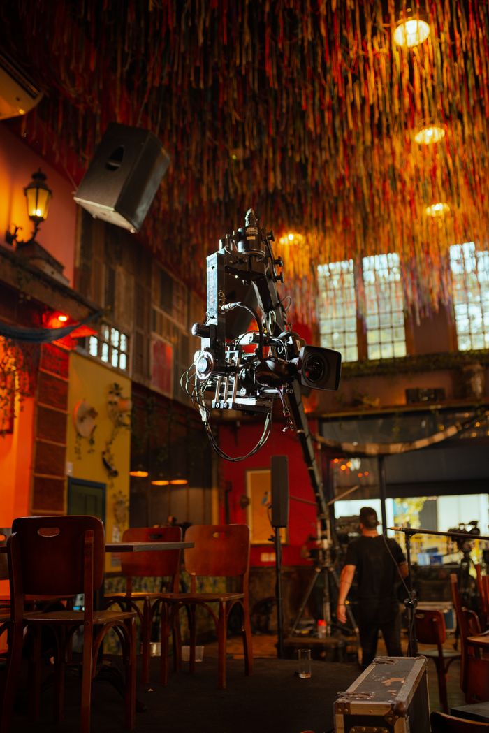 A professional video camera on a crane in a colorful, festive indoor studio setting.