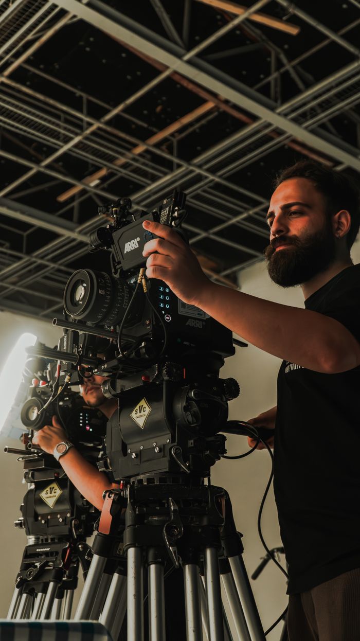 Film crew members operating professional cinema cameras in a studio setting, showcasing filmmaking equipment.